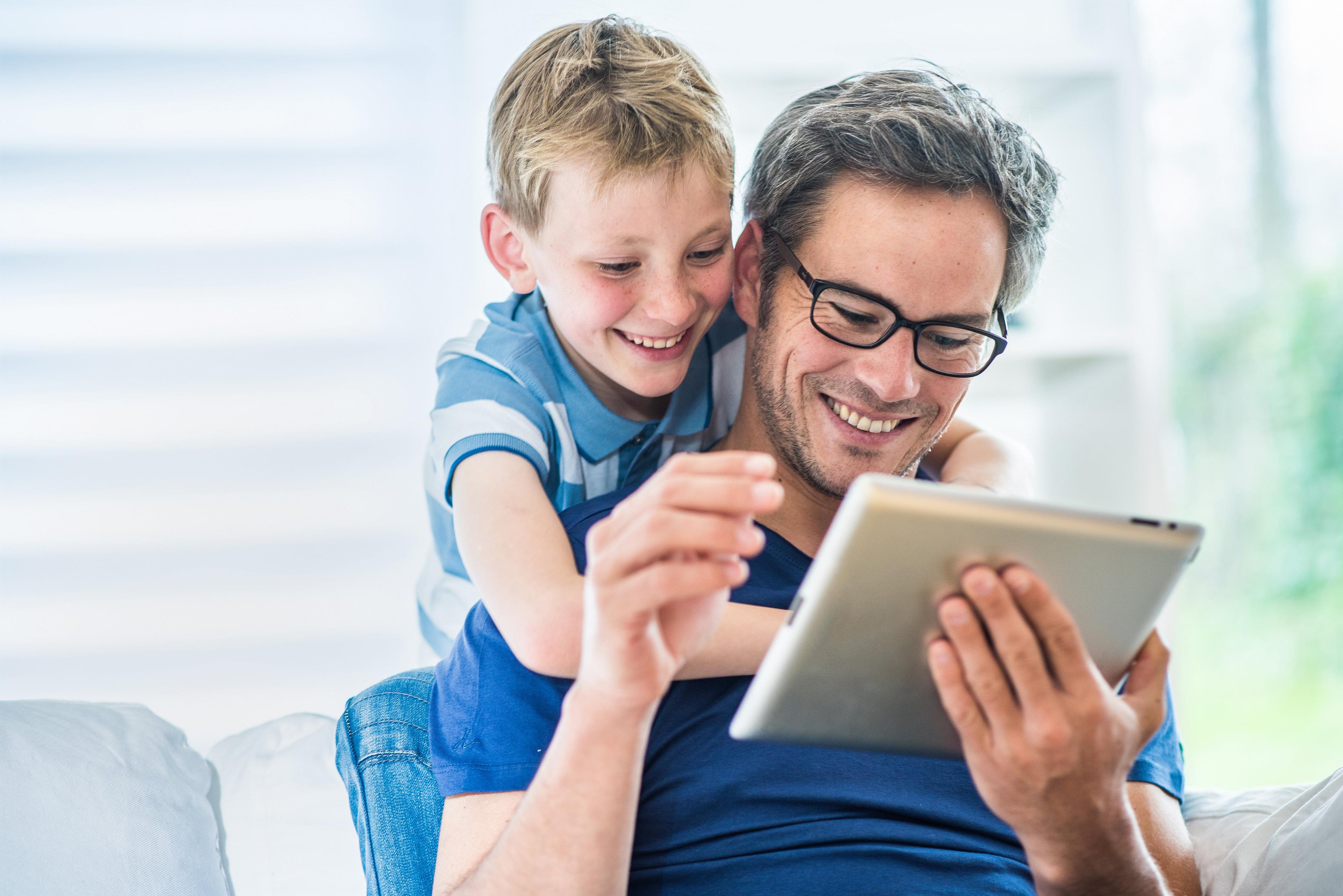 Vater und Sohn am Tablet auf dem Sofa sitzend