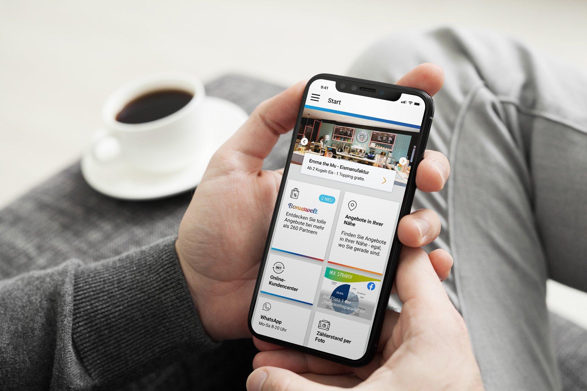 Mann hält Handy, das die Startseite der Stadtwerke App zeigt